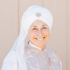 headshot of Mukta wearing white turban and smiling with grace